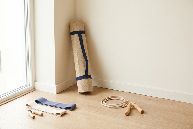 A home workout corner with a rolled exercise mat, resistance bands, a hand gripper and a jump rope